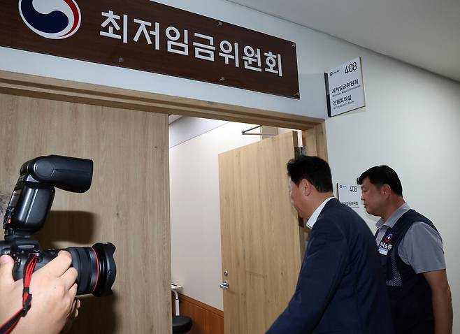 최저임금위원회 사용자위원인 류기정 한국경영자총협회 전무(왼쪽)와 근로자위원 류기섭 한국노총 사무총장이 10일 정부세종청사에서 열린 최저임금위원회 제12차 전원회의에서 민주노총 위원들이 심의를 거부한 채 퇴장해 회의가 정회된 후 밖에서 얘기를 나누고 들어오고 있다. 연합뉴스