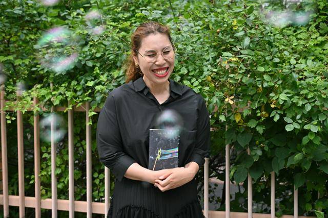 조승리 작가가 자신의 첫 소설집 '나의 어린 어둠'을 품에 안고 활짝 웃고 있다. 검은 어둠 속에서 오색 창연한 빛을 발하고 있는 책 표지의 비눗방울이 그의 주변을 떠다니고 있다. 정다빈 기자