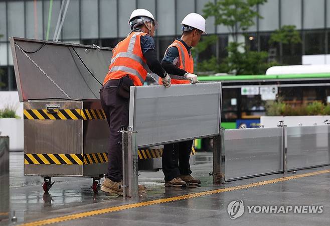 '물막이판 정리 중' (서울=연합뉴스) 김성민 기자 = 비가 내린 14일 서울 종로구 광화문광장에서 관계자들이 물막이판을 정리하고 있다. 2025.7.14 ksm7976@yna.co.kr