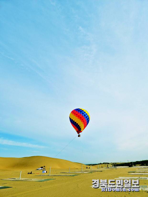 붉은 사막 위로 천천히 떠오르는 열기구가 광활한 대지를 가로지르며 환상적인 풍경을 선사하고 있다.