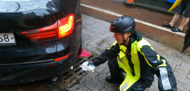 지난 17일 낮 12시 30분쯤 광주광역시 북구 중흥동 전남대 정문 도로에서 침수차량 배수작업하던 박선홍 소방위가 유실된 현금봉투를 발견한 모습. 광주 북부소방서