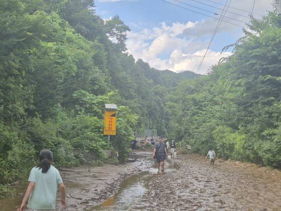 20일 오후 5시 30분경 경기도 가평군 조종면 마일리에 위치한 캠핑장 투숙객과 마을 주민이 흘러내린 토사에 뻘밭으로 변한 도로를 걸어서 대피하고 있다. 가평=전율 기자