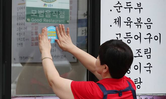 서울 성동구의 한 음식점 사장이 ‘민생회복 소비쿠폰 사용 가능 매장’ 스티커를 붙이고 있다. 소비쿠폰 사용처로 사람들은 전통시장과 마트, 음식점 등을 꼽았다. 성동구 제공