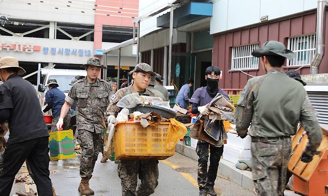 육군 32사단 장병들이 침수피해로 쑥대밭이 된 충남 당진 어시장에서 쓰레기로 변한 시장 상인들의 집기들을 치우며 수해복구를 돕고 있다. 당진=김정모 기자