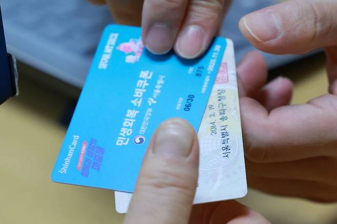 민생회복 소비쿠폰 신청이 시작된 21일 서울 송파구 거여2동주민센터에서 시민이 신청한 소비쿠폰을 받고 있다. 연합뉴스