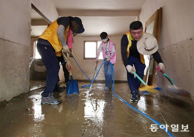 기록적인 폭우로 침수 피해를 입은 광주 북구 신안교 인근 주택에서 광주 지역 사회봉사 단체 회원들이 무더위 속에 복구 작업을 벌이고 있다. 박영철 기자 skyblue@donga.com