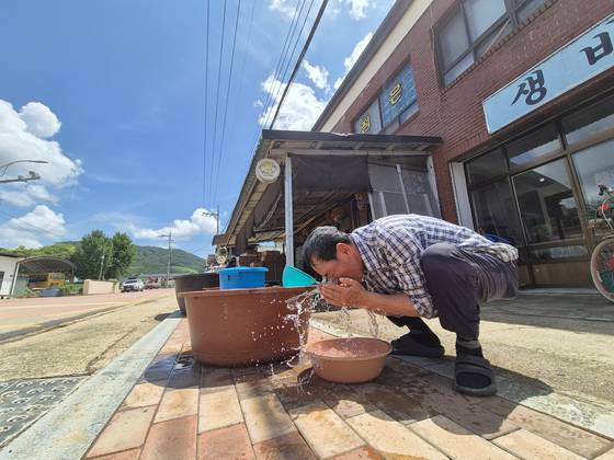 22일 낮 12시쯤 경남 산청군 생비량면 도동마을에서 한 호우 피해 70대 주민이 고무대야에 받아 놓은 물로 세수하고 있다. 19일 극한호우 이후 이 마을에 수돗물이 나오지 않으면서, 주민들은 지자체 등이 급수한 물을 사용하고 있다. 안대훈 기자