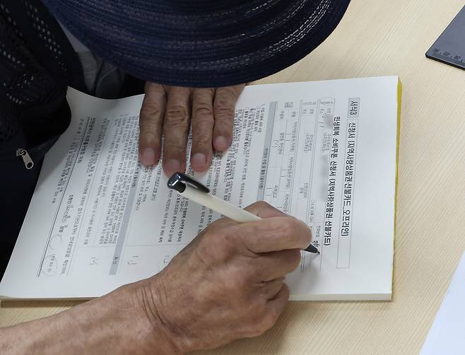 민생회복 소비쿠폰 1차 신청 첫 날일 21일 오전 인천 미추홀구 숭의1,3동 행정복지센터에서 한 어르신이 신청서를 작성하고 있다. 뉴시스