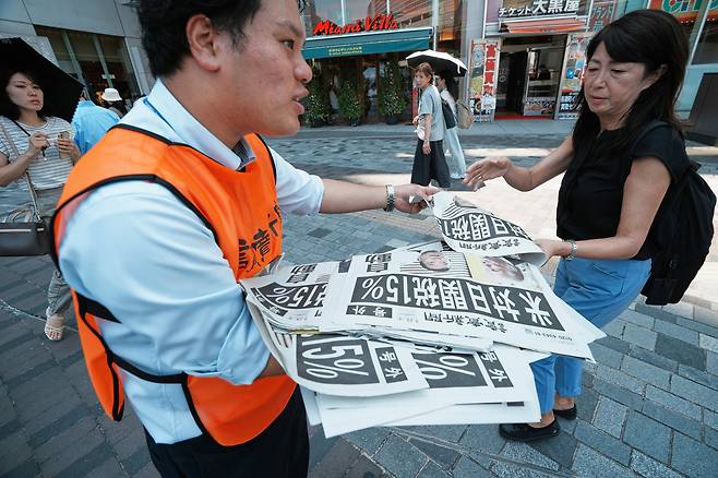 일본 요미우리신문 직원이 23일 도쿄 거리에서 미국 도널드 트럼프 행정부가 일본에 대한 상호관세율을 15%로 정했다는 기사가 실린 신문 호외를 배포하고 있다./AP 연합뉴스