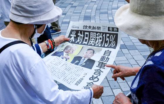 지난 23일 일본 도쿄에서 시민들이 '미국과 관세 협정 15%. 자동차 포함 합의' 제목의 호외를 읽고 있다. 로이터=연합뉴스