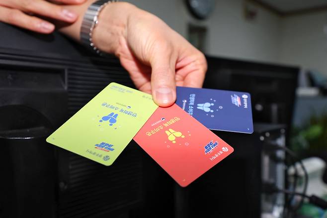 민생회복 소비쿠폰 지급 사흘째인 지난 23일 오후 광주 서구 농성1동 행정복지센터에서 한 직원이 서로 다른 색상의 현물 카드를 들고 있다. 광주시는 민생회복 소비쿠폰 선불카드를 소득별로 색상을 다르게 지급해 물의를 빚었다. /연합뉴스