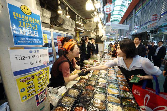 김혜경 여사가 25일 인천 계양구 계양산전통시장을 방문해 민생회복 소비쿠폰으로 상품을 구매하면서 상인과 인사를 나누고 있다. 왕태석 선임기자