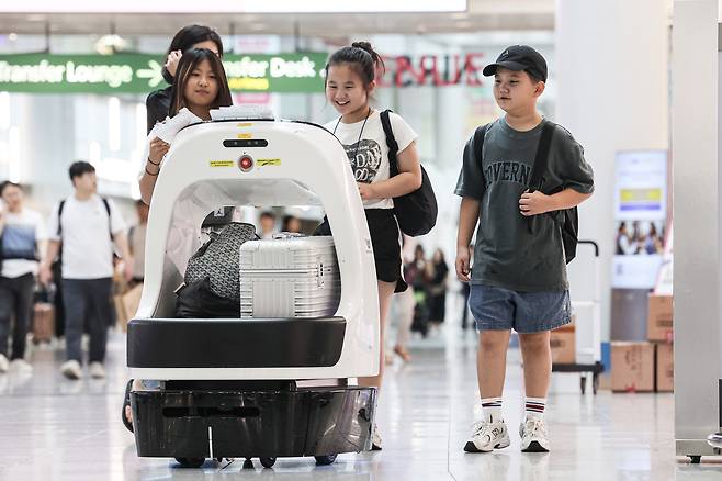 카트로봇에 캐리어와 짐을 맡긴 여행객들.