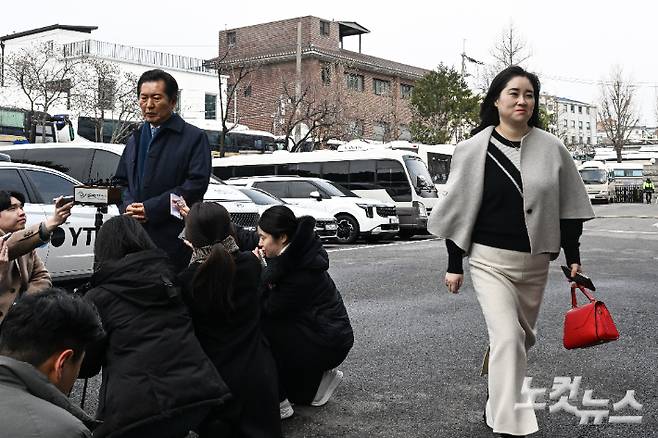 18일 서울 종로구 헌법재판소에서 열린 박성재 법무부 장관 탄핵 심판 첫 변론에 국회 탄핵소추위원장인 정청래 더불어민주당 의원이 참석하며 입장을 밝히고 있는 가운데 김계리 변호사가 웃으며 지나가고 있다. 류영주 기자
