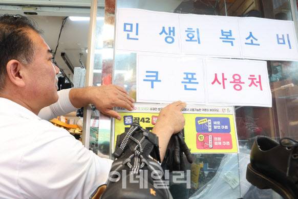 민생회복 소비쿠폰 지급을 하루 앞둔 지난 20일 서울 동작구 한 편의점에서 상인이 ‘민생회복소비쿠폰 사용처’ 현수막을 가게 앞에 부착하고 있다. (사진=이영훈 기자)