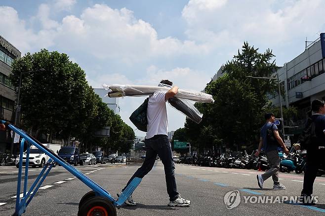 폭염 (서울=연합뉴스) 윤동진 기자 = 폭염이 이어지고 있는 28일 서울 동대문종합시장 인근에서 근로자가 원단을 옮기고 있다. 2025.7.27 mon@yna.co.kr