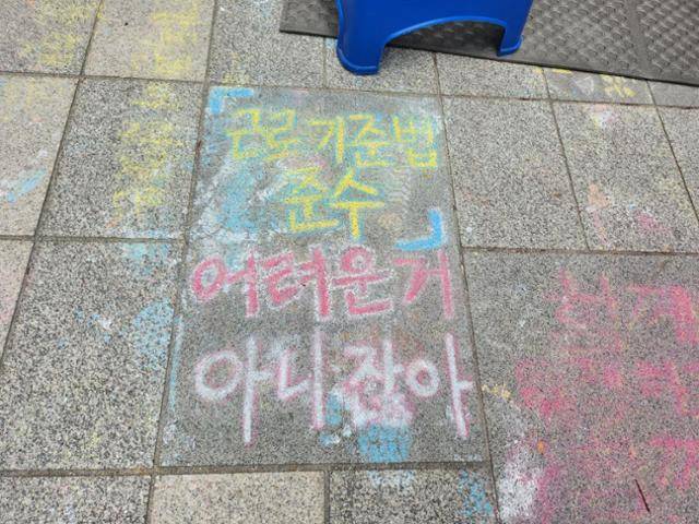 7일 서울 중구 서울지방고용노동청 앞 주얼리 노동자 농성장 바닥에 '근로기준법 준수, 어려운 거 아니잖아'라는 문구가 써 있다. 송주용 기자