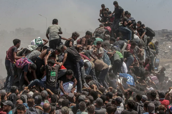 26일(현지시간) 팔레스타인 가자지구 남부 라파에 트럭 두 대가 들어서자 셀 수 없이 많은 가자 주민이 몰려들었다. EPA 연합뉴스