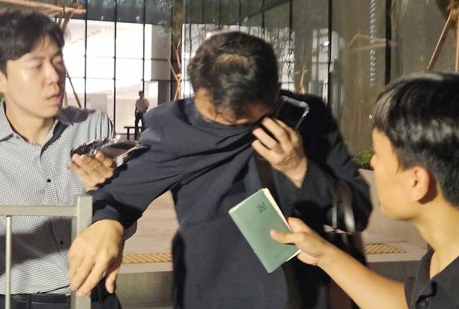 김건희 여사 오빠인 김진우 씨가 28일 김 여사 관련 의혹들을 수사하는 민중기 특별검사팀 사무실이 위치한 서울 종로구 KT광화문빌딩에서 조사를 마친 뒤 얼굴을 가린 채 특검 사무실을 나서고 있다. 김씨는 이른바 ‘양평 공흥지구 개발 특혜 의혹’의 핵심 당사자다. 2025.7.28 연합뉴스