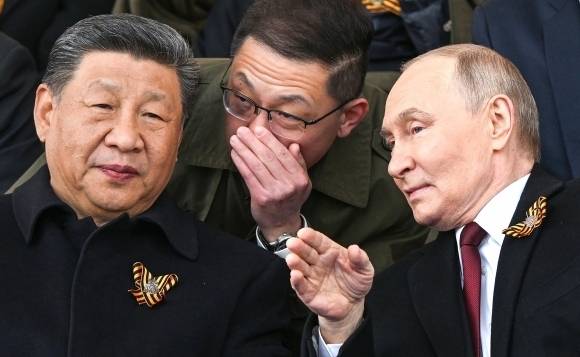 2025년 5월 9일(현지시간) 러시아 모스크바 붉은광장에서 열린 전승절 80주년 열병식을 참관하는 시진핑(왼쪽) 중국 국가주석이 블라디미르 푸틴(오른쪽) 러시아 대통령과 통역을 사이에 두고 대화를 나누는 모습. UPI 연합뉴스