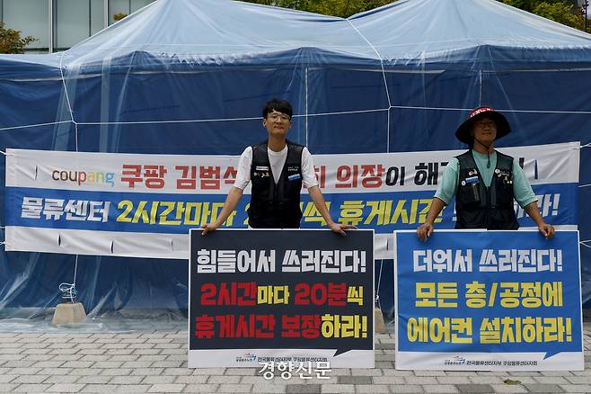 정동헌 공공운수노조 전국물류센터지부 쿠팡물류센터지회장(왼쪽)과 정성용 공공운수노조 전국물류센터지부장이 4일 서울 송파구 쿠팡 본사 앞 농성장에서 물류센터 내 폭염 대책 마련 촉구와 휴게시간 보장 등을 촉구하는 손펫말을 들고 있다. 문재원 기자