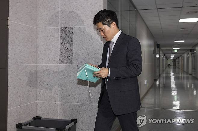 '주식 차명거래' 이춘석 의원실 폐지함에서 발견된 수첩 전달받은 경찰 (서울=연합뉴스) 황광모 기자 = 서울경찰청 금융범죄수사대 전담수사팀 관계자가 11일 주식 차명거래 혐의를 받는 이춘석 의원의 국회 사무실 압수수색 진행 도중 취재진이 이 의원실 출입문 앞 폐지함(왼쪽 아래 회색 상자)에서 발견한 수첩을 전달받은 뒤 이동하고 있다. 2025.8.11 hkmpooh@yna.co.kr
