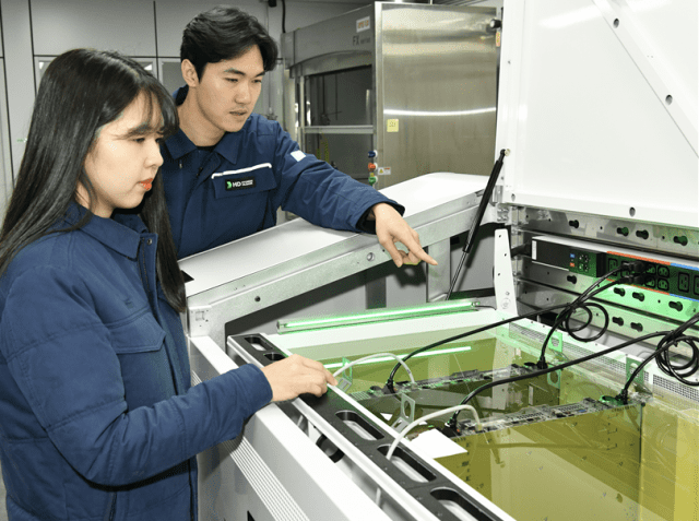 액침냉각설비에 담긴 냉각유와 서버를 테스트하고 있는 HD현대오일뱅크 직원들. (사진=HD현대오일뱅크)