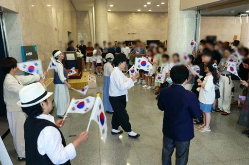 17일 전북 군산근대역사박물관을 찾은 방문객들이 손에 태극기를 든 채 연극 ‘빼앗긴 들에도 봄은 온다’ 관람에 앞서 설명을 듣고 있다. 군산시 제공