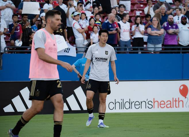 (몸을 풀고 있는 손흥민 뒤로 경기장을 찾은 한인 팬들과 태극기의 모습이 인상적이다)