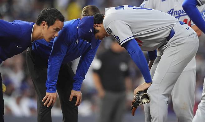 오타니가 지난 21일(한국시각) 콜로라도전에서 4회 투구 도중 강습타구에 허벅지를 맞은 뒤 허리를 숙여 트레이너와 함께 상태를 살피고 있다. AP연합뉴스