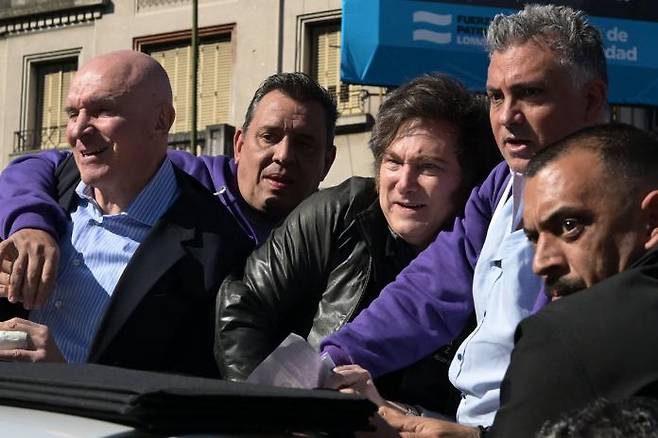 아르헨티나 대통령 하비에르 밀레이 아르헨티나 대통령(오른쪽에서 세 번째)이 27일(현지시간) 로마스데사모라에서 총선 유세 카퍼레이드를 하던 도중 군중이 자신에게 물건을 던지자 반응하고 있다. AFP연합뉴스