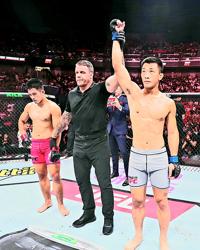 AFC 웰터급 챔피언 김상욱이 2025년 8월 상하이다우타이 Road to UFC 시즌4 라이트급 토너먼트 4강전 승리 선언을 받고 있다. 왼쪽은 탈락을 아쉬워하는 중국 우슈 산타 전우훈 전국대회 우승자 런야웨이. 사진=TKO