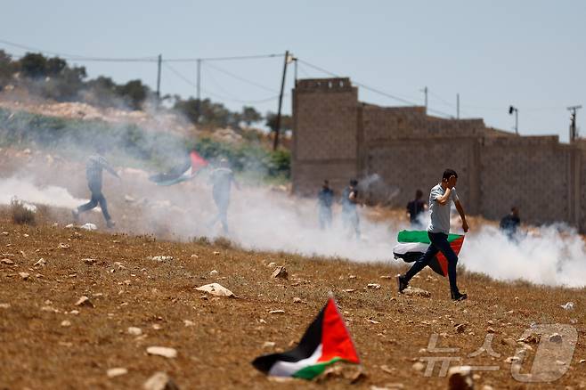 이스라엘이 점령한 서안지구 제닌 근처 라바에서 시위를 벌이고 있는 팔레스타인인들과 경계를 서고 있는 이스라엘군. 2025.7.18 ⓒ 로이터=뉴스1 ⓒ News1 김경민 기자