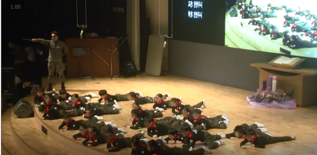 지난해 12월 서울의 한 대안교육기관 1,2학년 어린이들이 한 교회에서 붉은 색 스카프와 군복, 군화 차림으로 교관의 지휘에 따라 포복 자세를 하고 있다. 이 아이들은 공교육 대신 당국의 손길이 깊이 미치지 않은 교회 학교에서 초중고교 생활을 한다. 행사가 열린 교회는 대안교육기관과 무관하며 장소만 빌려준 것으로 알려졌다. 이 학교는 이 기사에 나온 서아(가명), 도현(가명)이가 교육 받은 곳과는 다른 학교이다. 유튜브 캡쳐