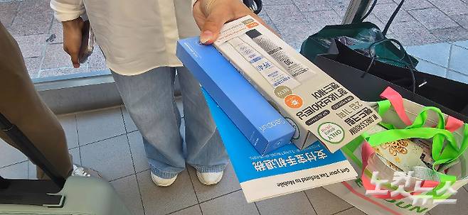 선크림, 마스크팩 등 제품을 한 손에 든 외국인 관광객. 쇼핑백 안에 구매한 제품이 담겨 있다. 양지훈 인턴기자