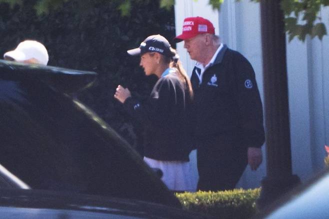 지난달 30일(현지시간) 도널드 트럼프 미국 대통령이 자신의 건재함을 과시하고자 공개한 골프장 방문 사진. 손녀인 카이 트럼프와 골프장에 들어가고 있다. AP연합뉴스