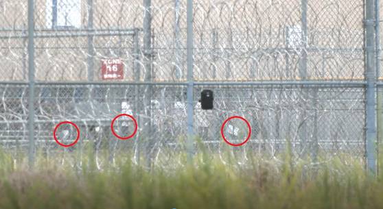 현지시간 6일 미국 조지아주 포크스턴에 위치한 불법 체류자 구금시설에 수감된 한국인 근로자 300여명이 시설내 조사실로 줄을 지어 이동하고 있다. 이들은 푸른색 수용복 하의를 입었고, 손에는 서류(붉은색 원)를 한장씩 들고 있었다. 포크스턴=강태화 특파원