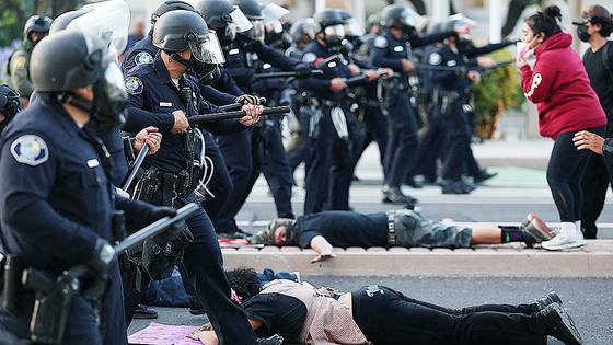 지난 6월 9일(현지시간) 미 캘리포니아주 산타아나에서 이민세관단속국(ICE)의 급습 보고가 접수된 후, 진압 장비를 갖춘 경찰이 미국 시민권 및 이민국(USCIS) 산타아나 현장 사무소 밖 거리에 누워 있는 시위자들을 지나쳐 전진하고 있다. AFP=연합뉴스