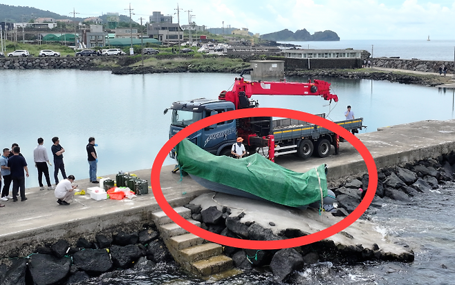 해경과 경찰 등 관계자들이 8일 오전 제주시 한경면 용수리 해안가에서 이날 오전 발견된 미확인 보트를 조사해 인양하려 하고 있다. 연합뉴스