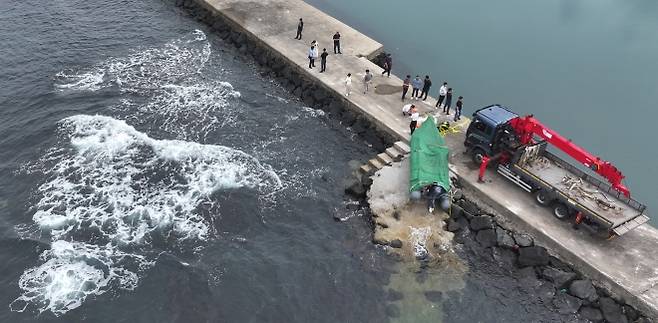제주 해안서 발견된 정체불명의 보트 - 해경과 경찰 등 관계자들이 8일 오전 제주시 한경면 용수리 해안가에서 이날 오전 발견된 미확인 보트를 조사해 인양하려 하고 있다. 연합뉴스