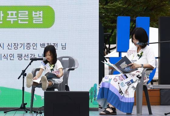 지난 8일 장기기증의날 기념식에 참석한 뇌사 장기기증인 이승준 군의 가족 윤정원(44)씨와 이예지(6)양이 생명나눔 동화 ‘세상에서 가장 특별한 푸른 별’을 낭독하고 있다. 사진 사랑의장기기증운동본부