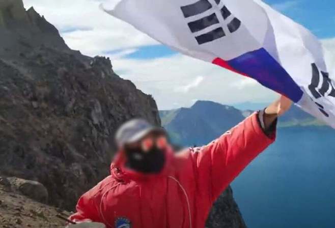 한 유튜버가 백두산 천지에서 태극기를 흔들자 중국 현지 관계자가 이를 제지하는 모습이 포착된 영상. 유튜브 캡처