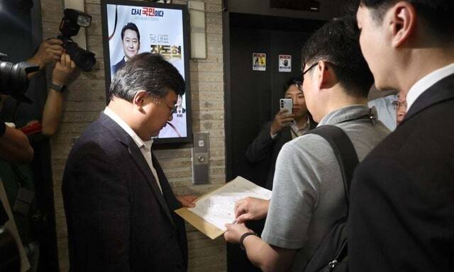 18일 서울 여의도 국민의힘 중앙당사 현관 엘리베이터 앞에서 김건희 특검팀이 제시한 압수수색 영장을 국민의힘쪽 변호사가 읽고 있다. 윤운식 선임기자 yws@hani.co.kr