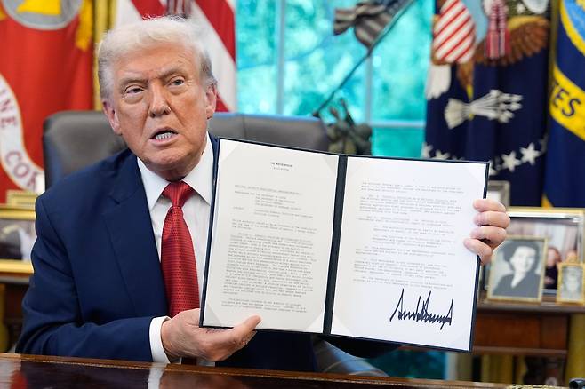 도널드 트럼프 미국 대통령이 25일(현지시각) 미국 워싱턴 D.C. 백악관 집무실에서 행정명령에 서명한 뒤 들어 보이고 있다. /AP·연합뉴스