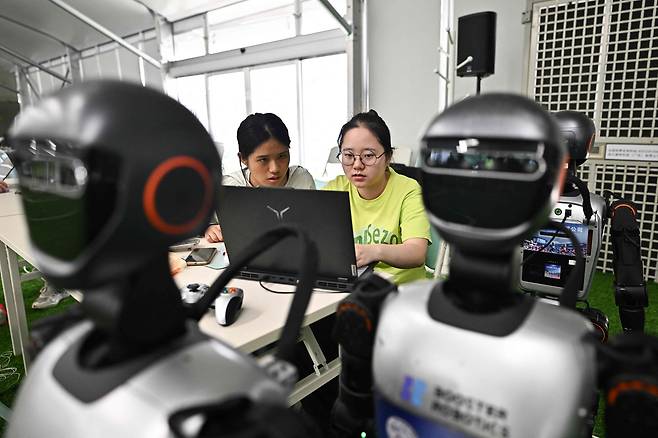 지난달 4일 베이징에서 열렸던 세계 휴머노이드 로봇 대회를 앞두고 중국 대학생들이 휴머노이드 로봇을 설치하고 있다. / AFP 연합뉴스
