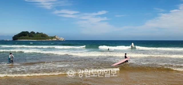 ▲ 보드를 쥐고 스팟으로 향하는 한 서퍼와 금구도가 조화를 이루는 이곳은 영화 ‘파이란’의 배경지로 파도를 타고 보는 화진포 호수는 브래드 섬 부럽지 않은 장관을 연출한다.