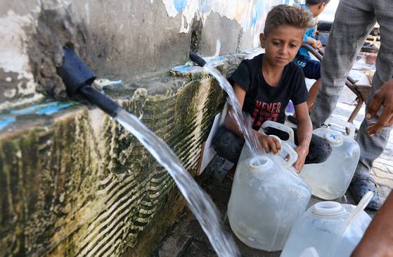 8일(현지시간) 가자지구 중부 데이르 알-발라에서 한 난민 팔레스타인 소년이 컨테이너에 물을 채우고 있다. 로이터=연합뉴스