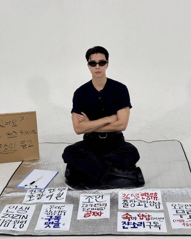 NCT의 X(구 트위터) 계정에 ‘쟌소리 coming soon’이라는 문구와 함께 공개된 사진. 은색 돗자리에 앉아 길거리 상담소 콘셉트를 표현하고 있다./NCT X(구 트위터) 계정