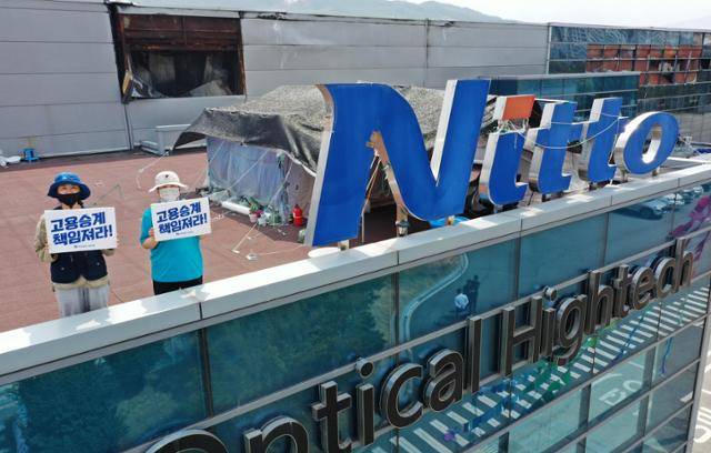 4월 경북 구미시 한국옵티칼하이테크 고공농성장에서 해고노동자 박정혜(왼쪽), 소현숙씨가 '고용승계 책임져라'라고 적힌 손피켓을 들고 있다. 구미=홍인기 기자
