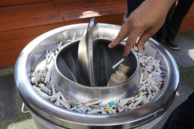 서울 시내의 한 흡연부스에서 시민이 담배꽁초를 버리고 있다(자료사진).ⓒ뉴시스